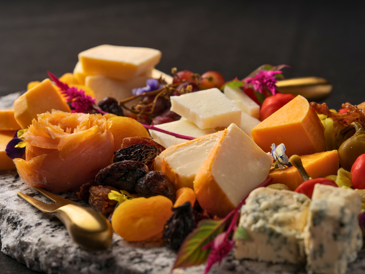 “A gourmet cheese board with artisanal cheeses, charcuterie, fruits, and accompaniments, styled on a wooden board at Carvers on 19