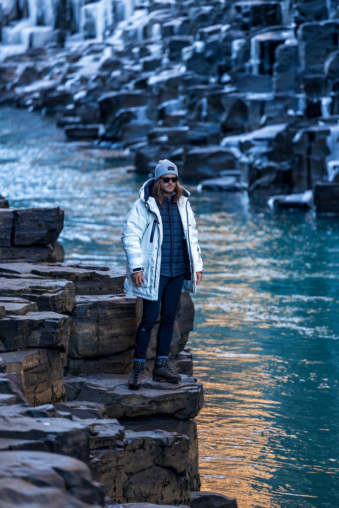 Rúrik Gíslason stands on rocks at the edge of Stuðlagil canyon in East Iceland, with the river at his feet.