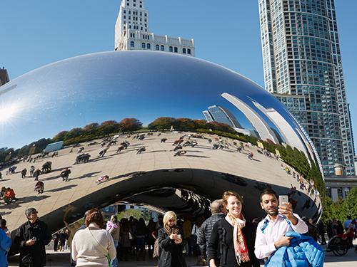 The Bean in Chicago, pictured with tourists taking a selfie in front of it 