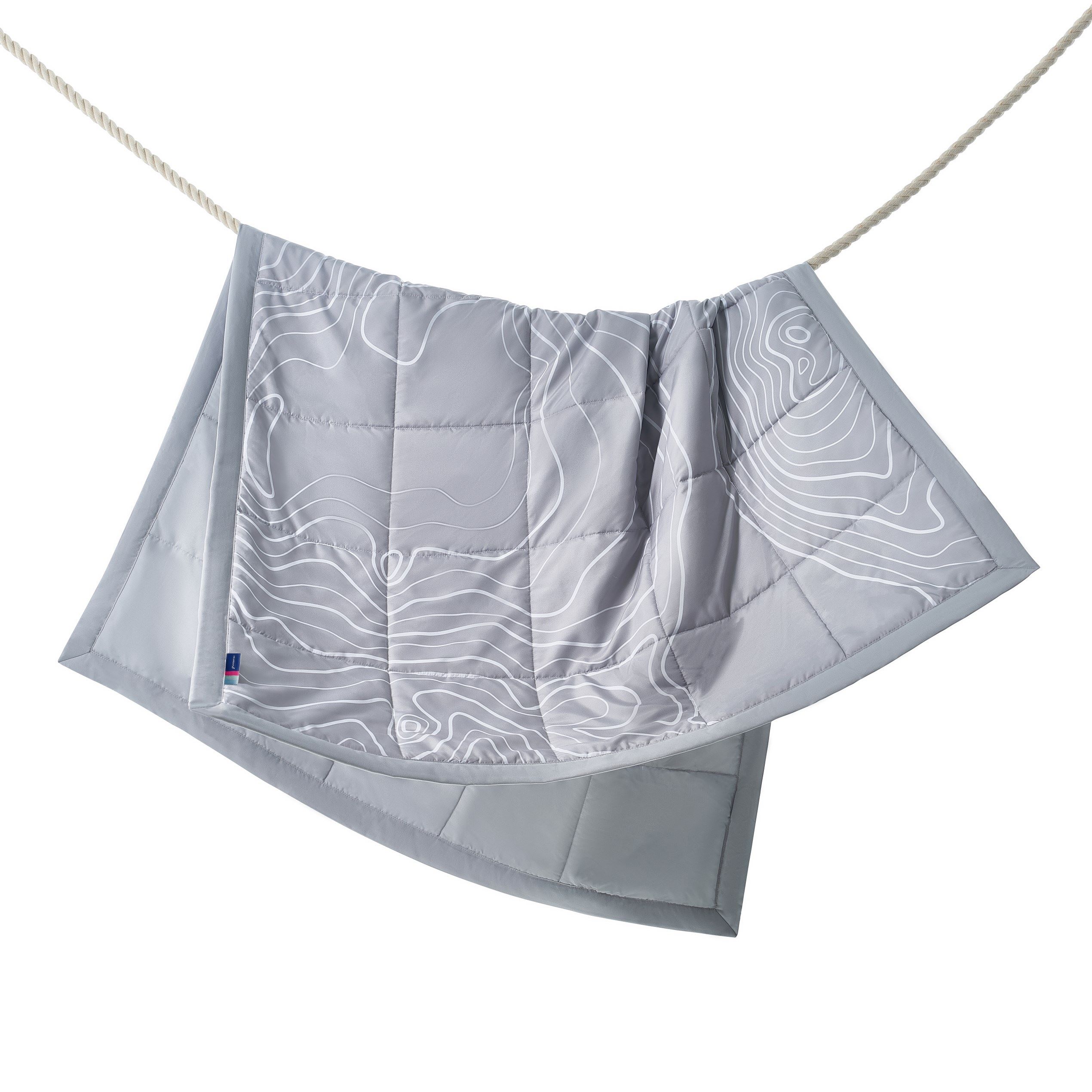 Our new onboard Saga Premium quilted blanket is gray with white topograpgic lines - photographed hanging over a rope