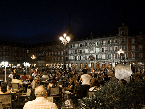 A scene of people enjoying food at an outdoor seating area of a restaurant in Plaza Mayor in Madrid 