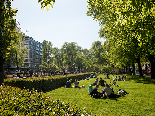 People enjoy sitting with friends in Esplanade Park, Helsinki on a sunny day 