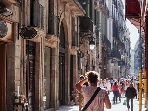 A person with their back to the camera walks down a busy shopping street in Barcelona, Spain 