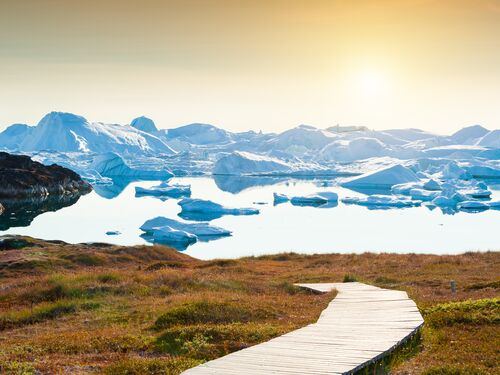 le soleil se couche sur une baie remplie d'icebergs