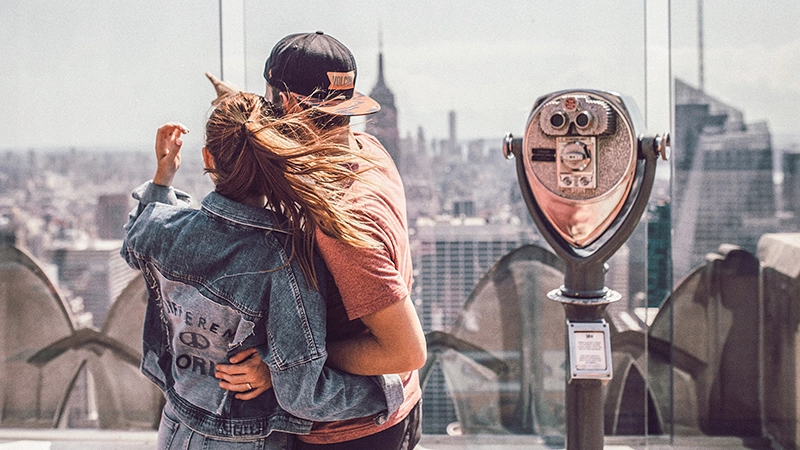 a couple seen from behind, looking at a city skyline