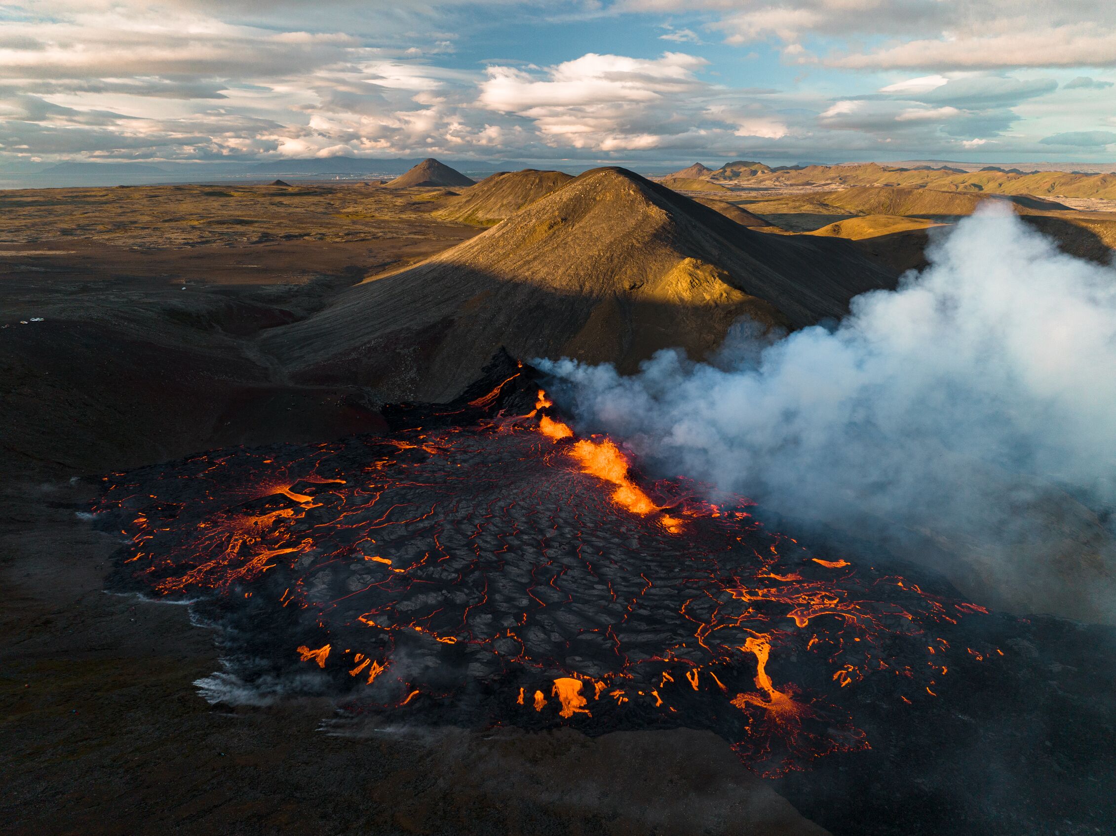 drone image of new lava field from 2022 volcanic eruption with hills in background