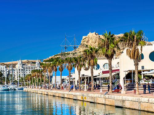 The harbour in Alicante pictured on a bright summer day with blue skies and several boats docked 