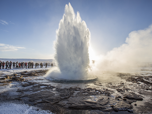Geysir, on the Golden Circle route, pictured here going off and blowing hot steam into the air while people watch 