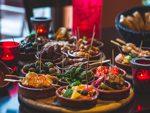 A mezze board of olives and other nibbles laid out in small bowls on a platter 