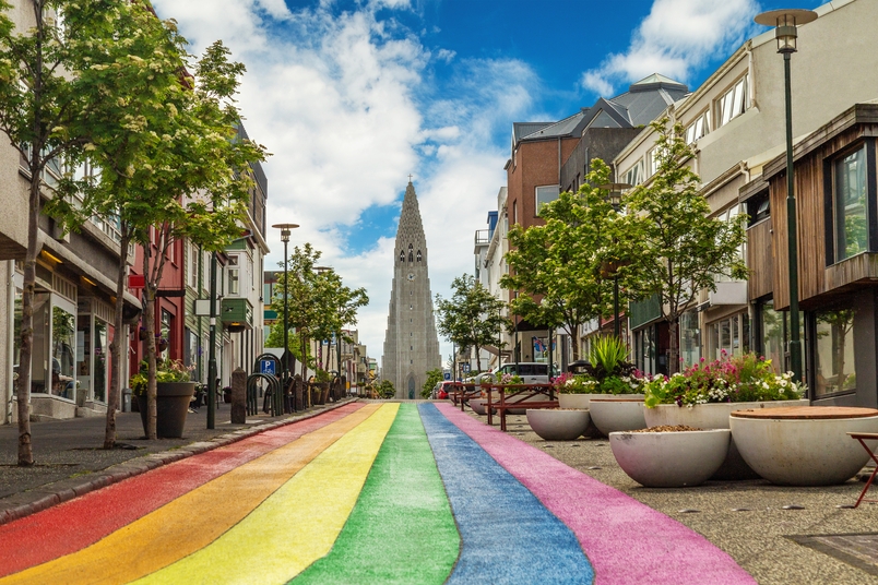 Photo of Skólavörðustígur street in downtown Reykjavík, with rainbow colors painted on the road and a view of Hallgrímskirkja in the distance