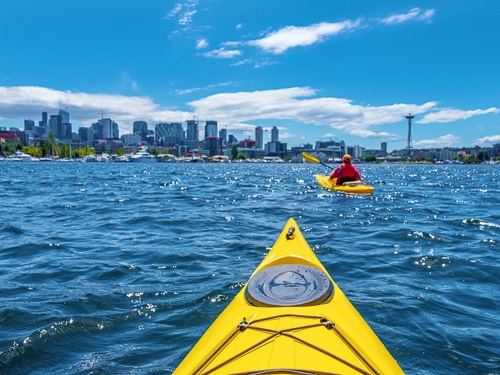 The view from a kayak in the water close to Seattle, with another kayak moving ahead 