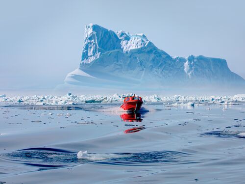 un bateau rouge devant de grands icebergs