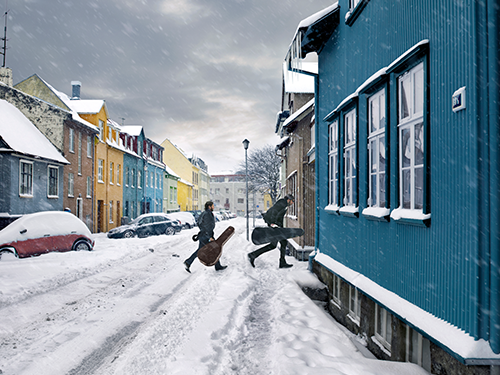 Zwei Personen mit Musikinstrumenten betreten ein blaues Haus in einer stark verschneiten Straße in Reykjavík 