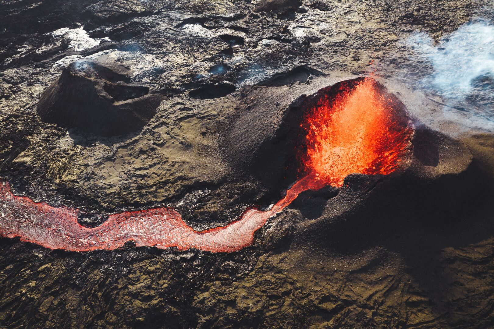 A close up image of the erupting volcano in Iceland with lava spurting up and pouring out the side