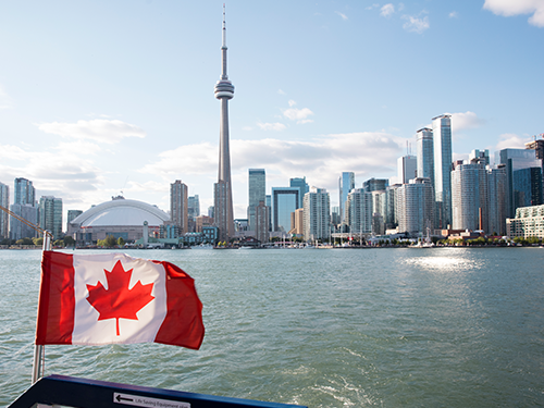 Toronto séð frá báti á Lake Ontario, kanadíski fáninn í forgrunni.