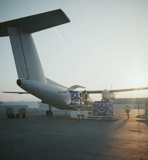 the rear of an electric-powered aircraft with a door open and two members of staff loading the vessel with energy capsules