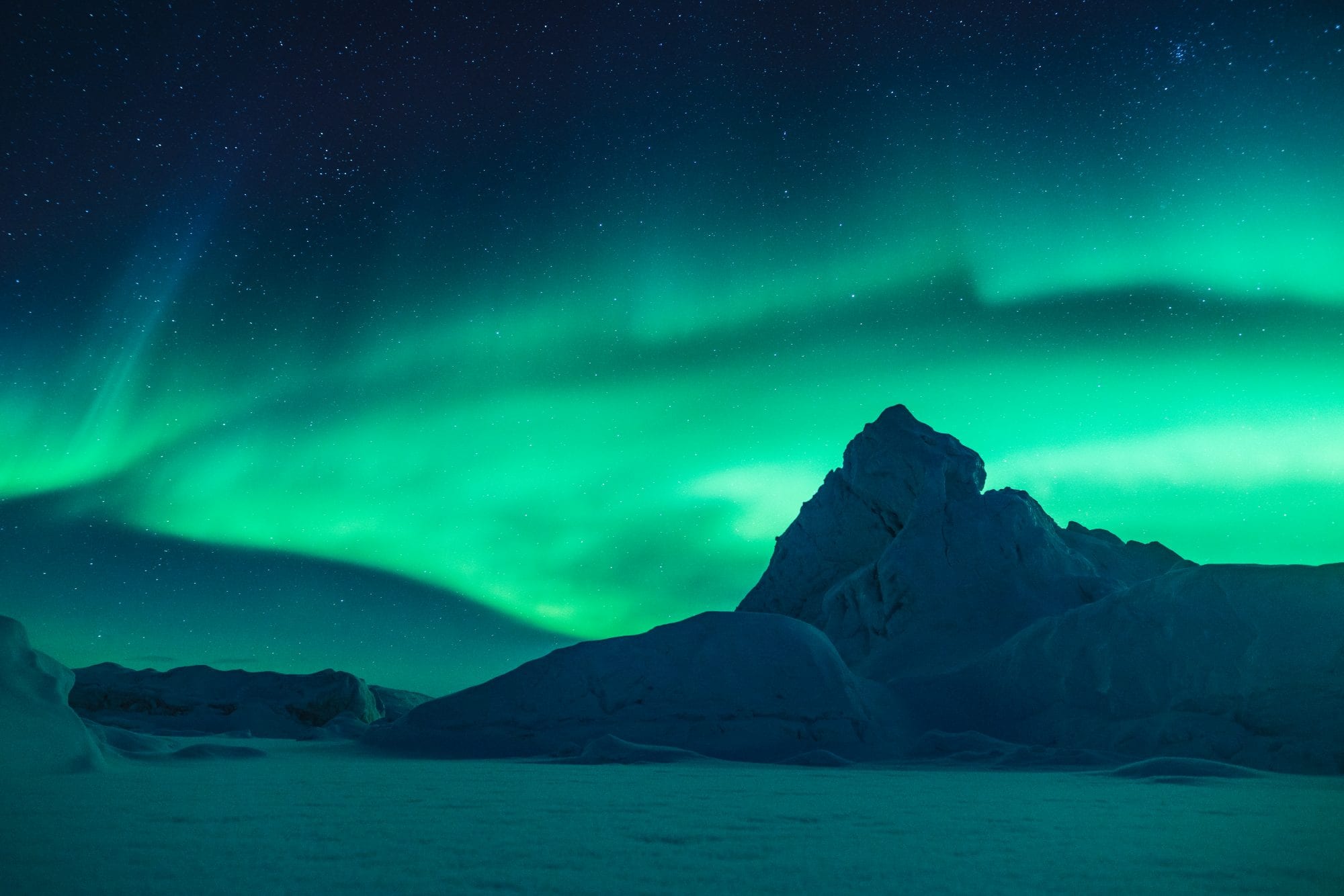 A snowy Arctic scene lit up by the Northern Lights display overhead