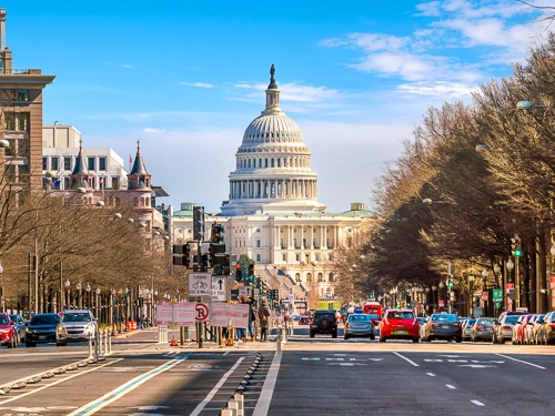 A street level scene of the bustling Washington DC in USA, with the Capitol building in the shot 