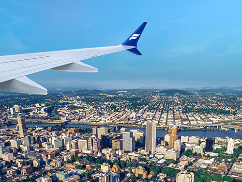 The wing of an Icelandair plane in the sky above Portland on a blue sky day 