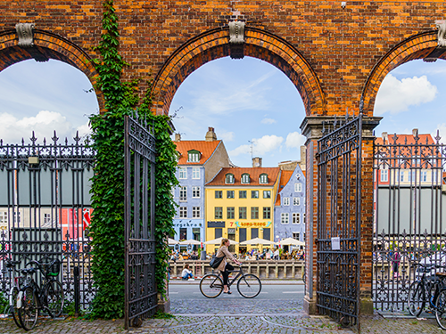 A person is cycling on a bike along the canal, pictured here between two sides of an arch