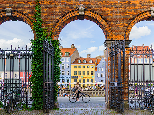 Kona hjólar meðfram Nyhavn í miðborg Kaupmannahafnar