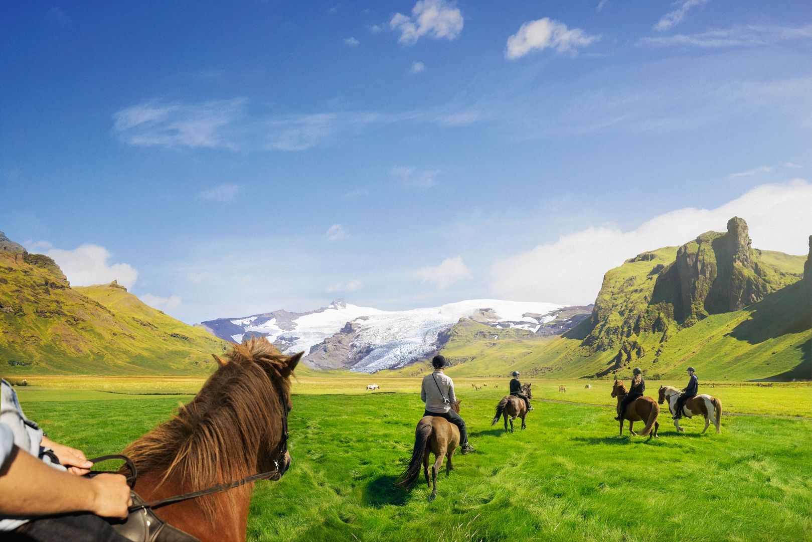 a group of horses riding through the Icelandic countryside