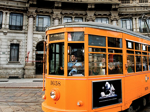 A man driving a yellow tram down the streets of Milan, Italy 