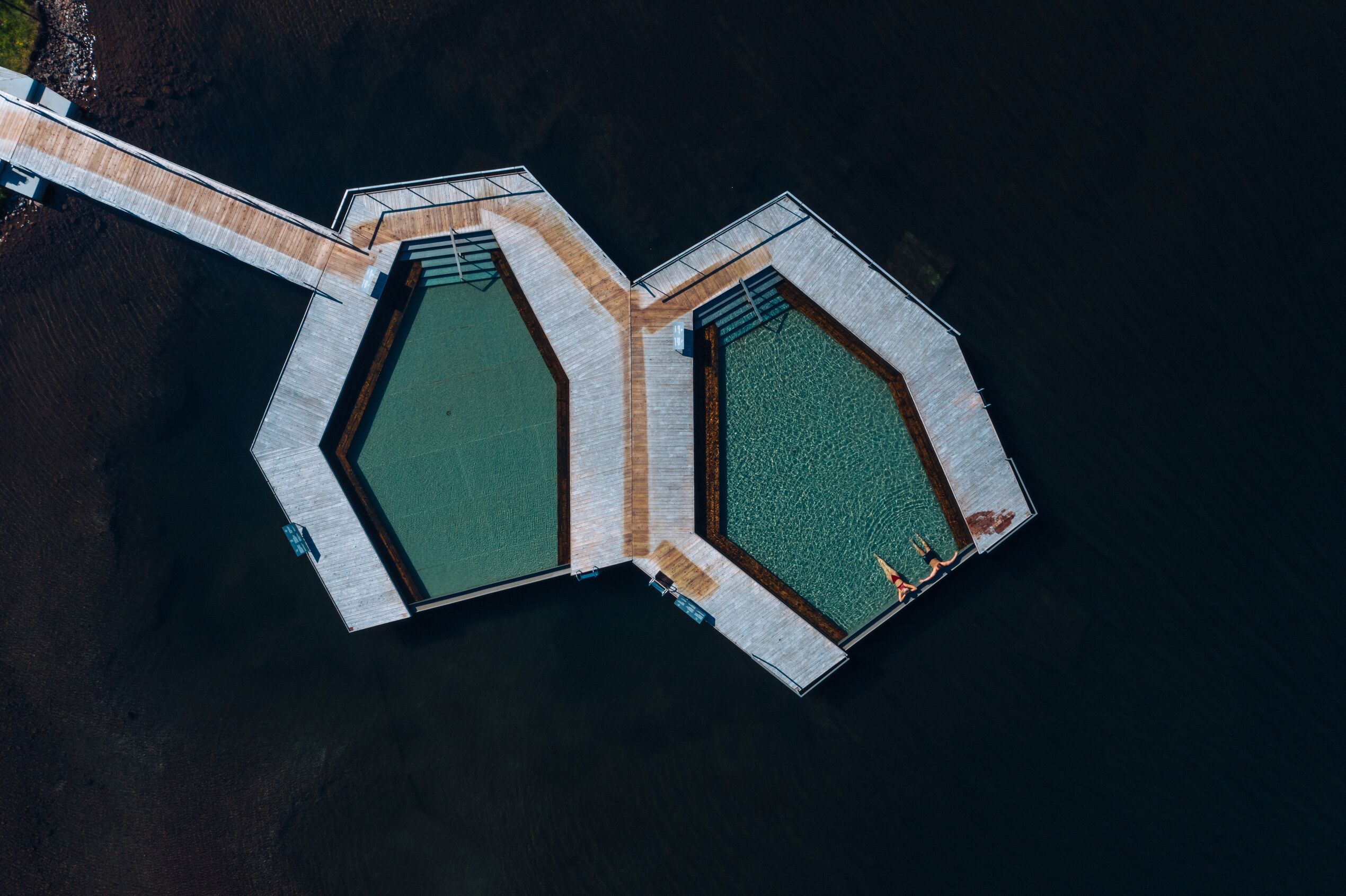 aerial image of a man and a woman bathing in Vök baths, Egilsstaðir. The bath is built into a lake as the hot spring emerges from the bottom of the lake.