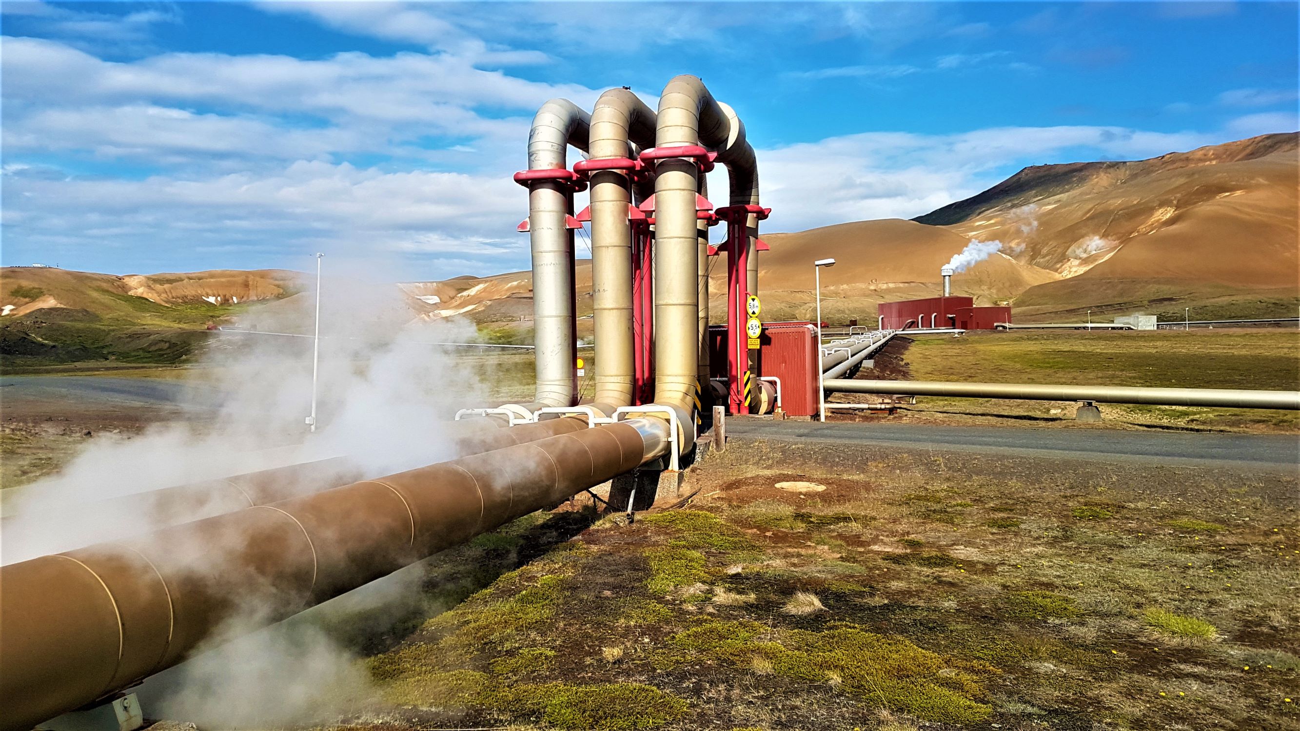 A geothermal power plant in Iceland showing the overground pipes with steam pouring out