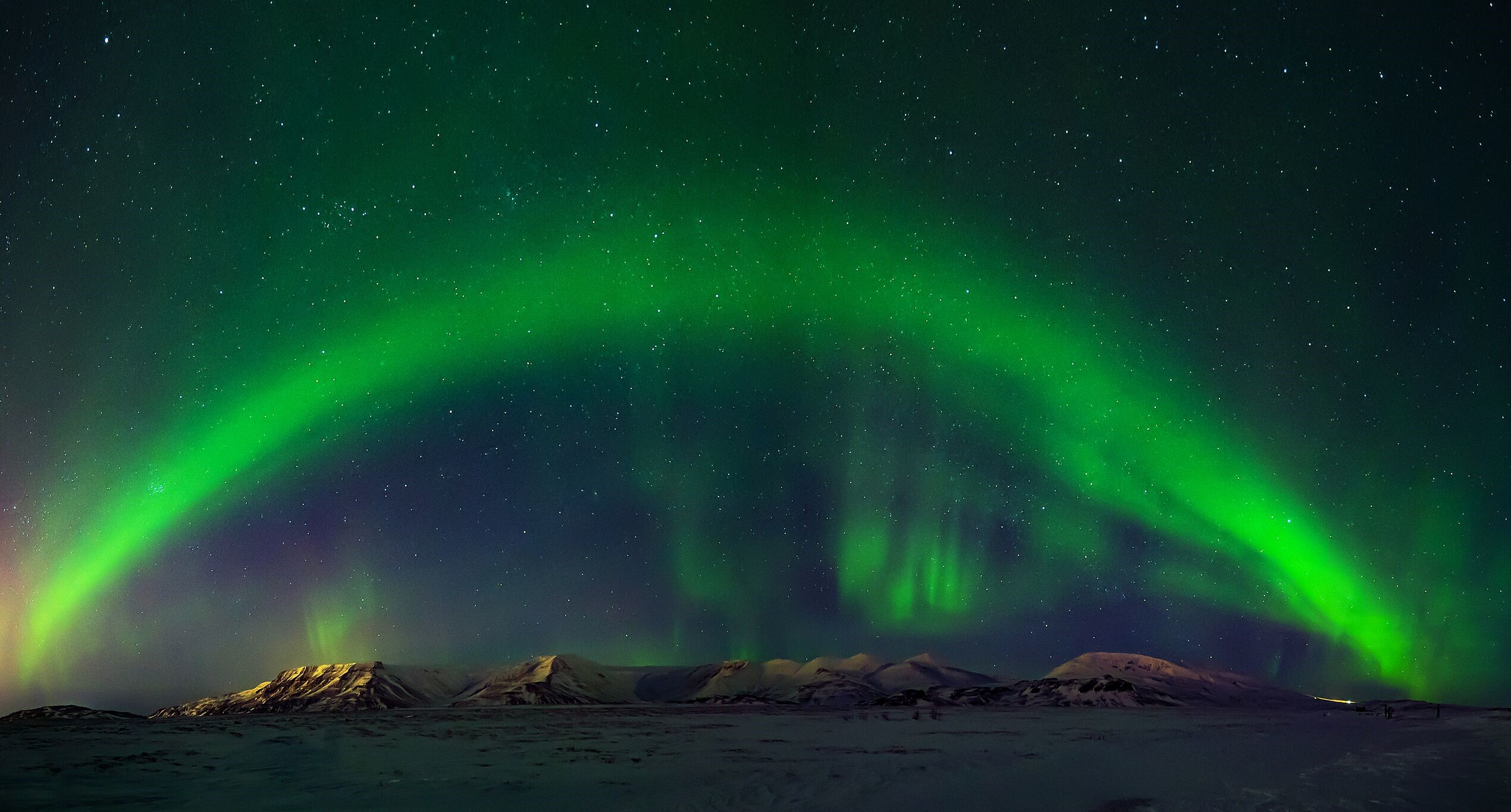The northern lights arc above the beautiful natural Icelandic landscape