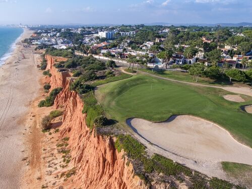 a golf course stretches along the Algarve coast