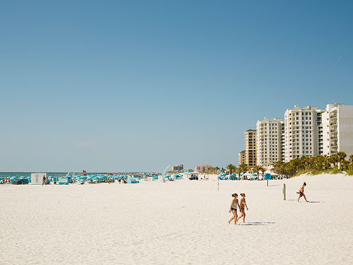 People in the distance walk on the bright white sandy beach in Orlando, USA 