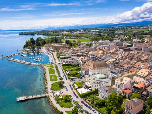 A birds eye view of Geneva in Switzerland on a bright sunny day, with the harbor cove visible  
