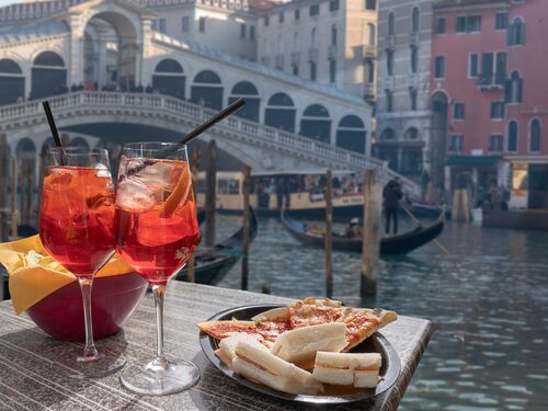 an aperol spritz and pizza at a canal-side restaurant in Venice