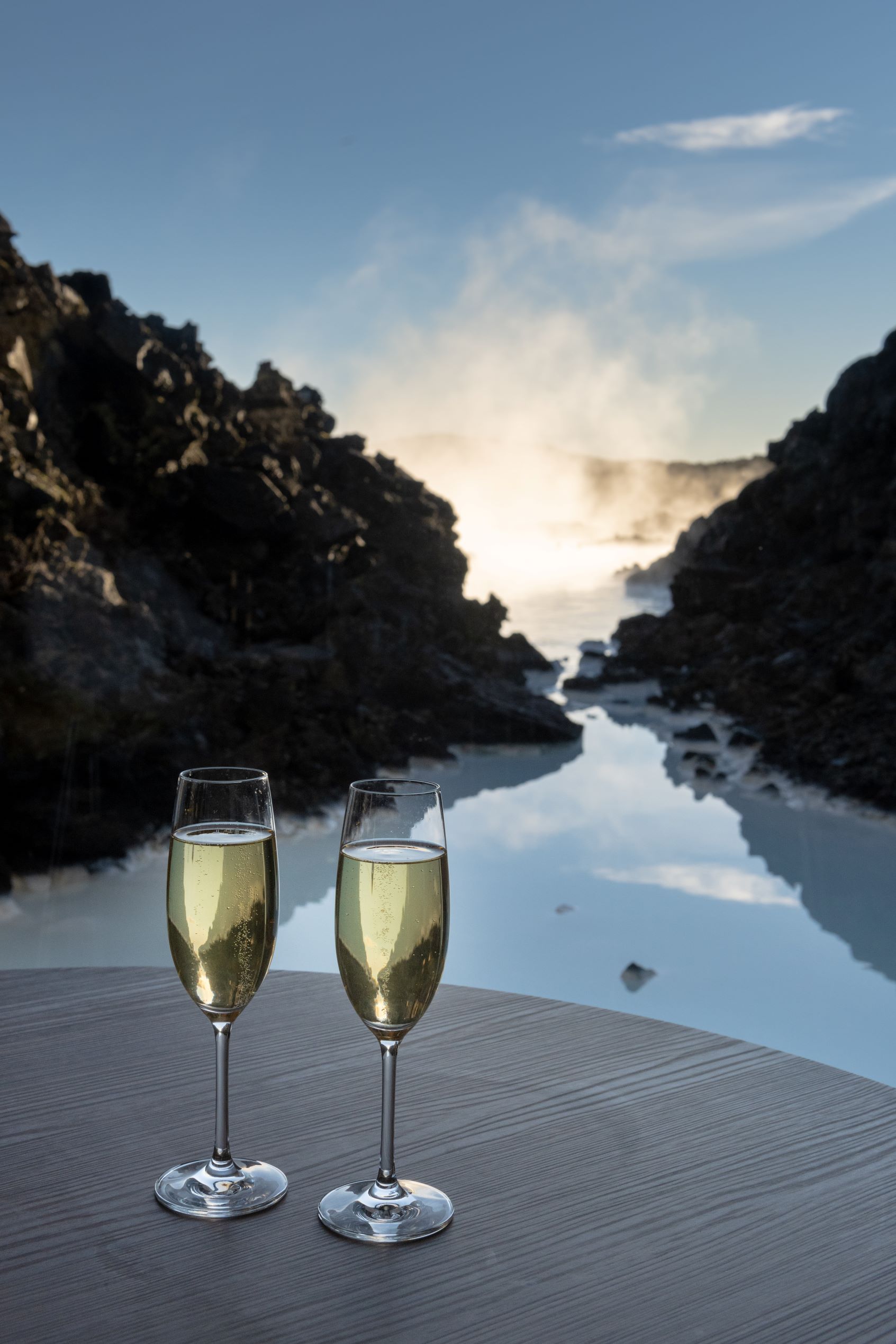 two glasses of champagne sit on an indoor table with a view out the window of the Blue Lagoon