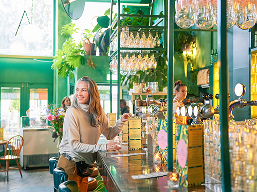 A woman is standing at a restaurant bar in Amsterdam, ready to make an order