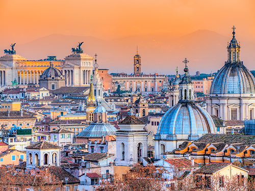 A cityscape picture of Rome, Italy, pictured at dawn with the sky a bright orange color 