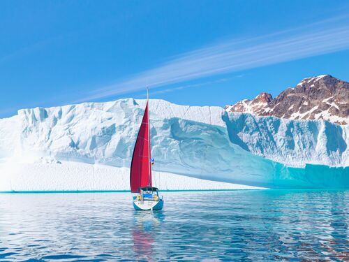un voilier devant un iceberg avec une eau bleue limpide