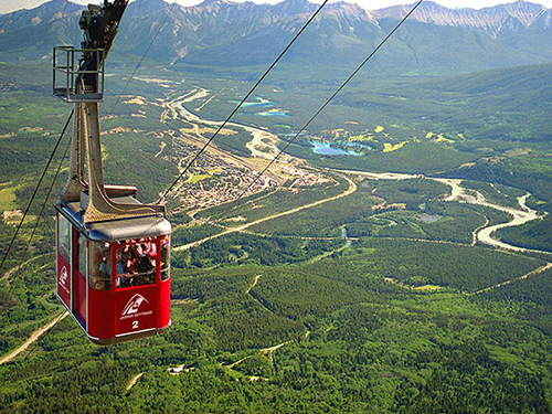 A view of the natural green landscape in Canada, with a red chair lift in picture 