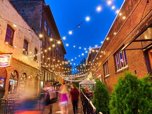 A view of the bustling city life in Portland, OR, with fairy lights lit up overhead the street view 