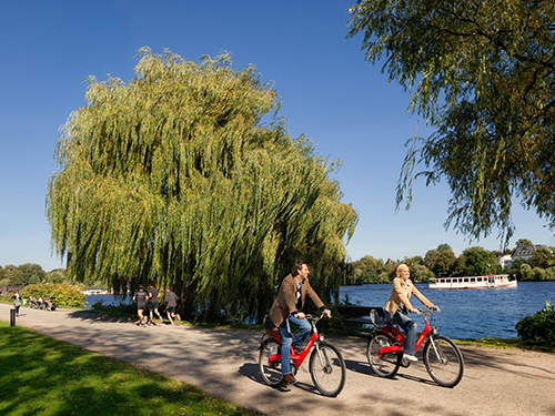 Two people cycle through the park in Hamburg, Germany
