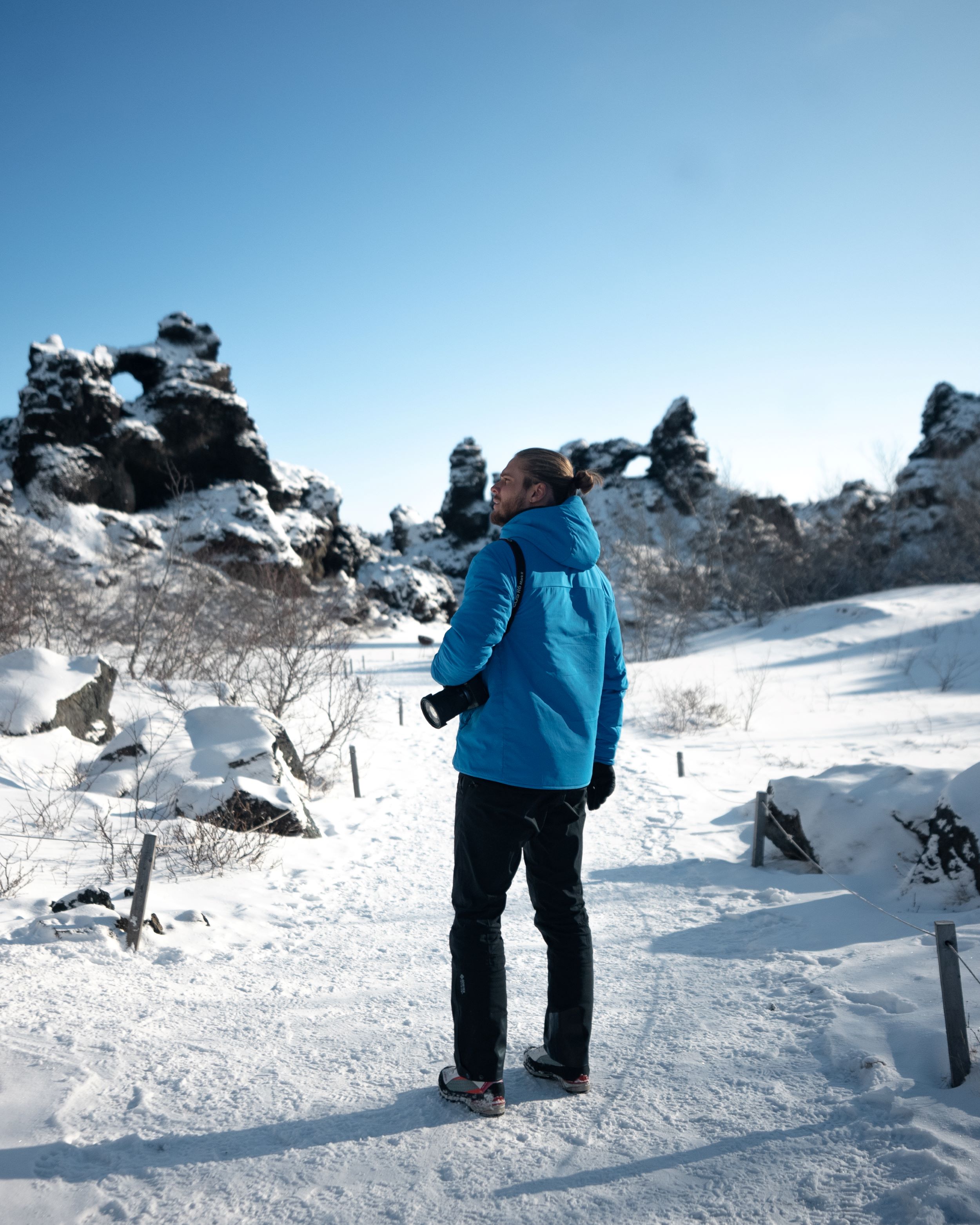 A view of Rúrik Gíslason standing on a snowy path and looking at the lava sculptures of Dimmuborgir in the Mývatn area of North Iceland.