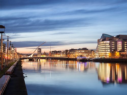 A cityscape of Dublin by the water with the city lit up at night 
