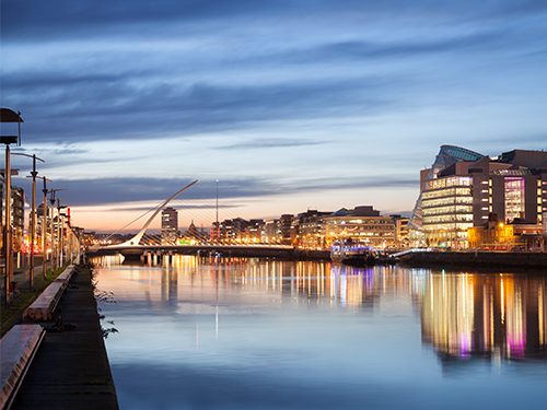 A cityscape of Dublin by the water with the city lit up at night