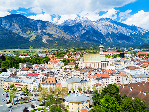 A birds eye view of the city of Innsbruck pictured with the picturesque town in the foreground and mountains in the background.