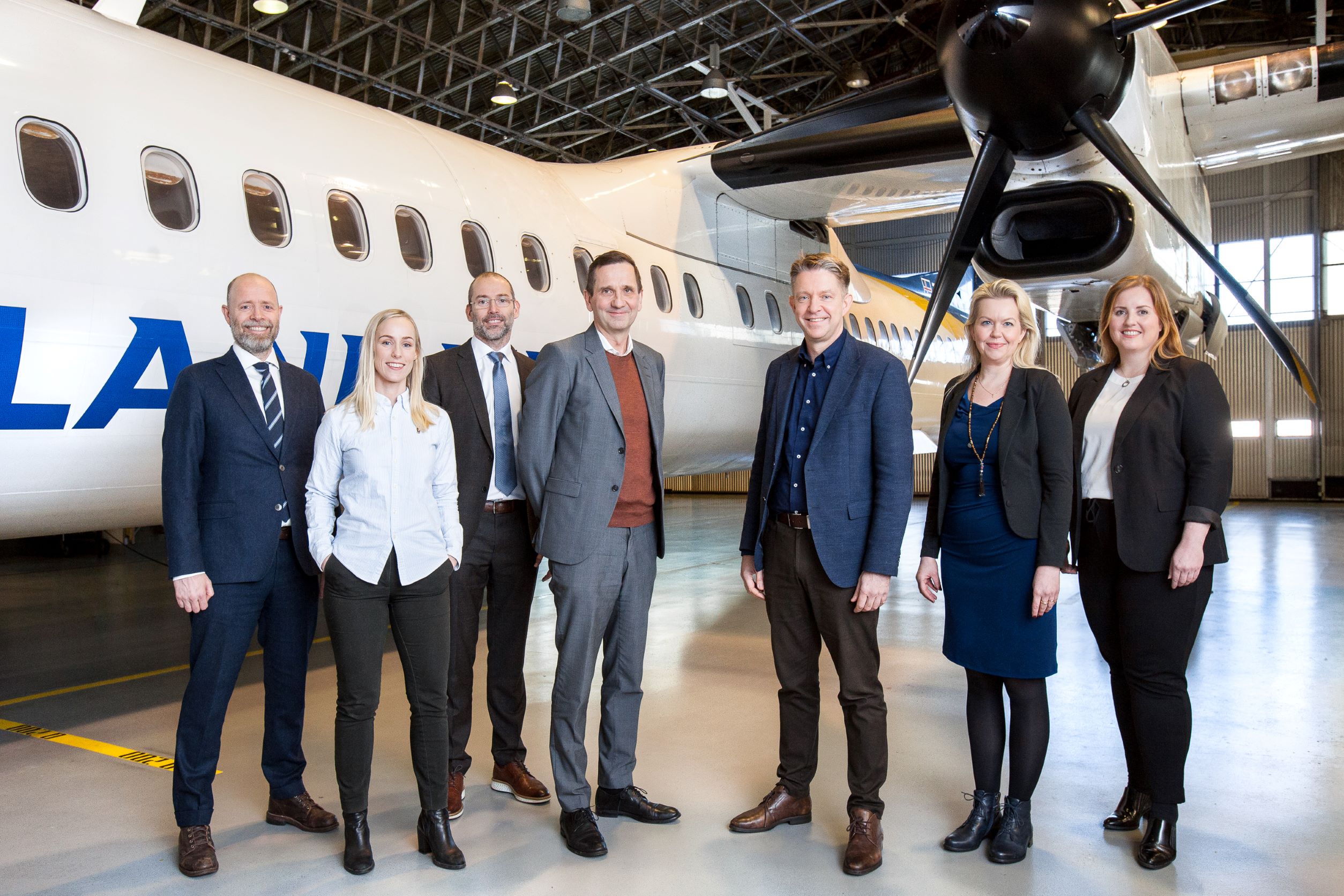 Representatives of management from Icelandair and Landsvirkjun stand in front of a plane in a hangar
