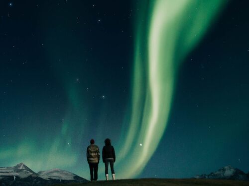 a couple looks up at the northern lights