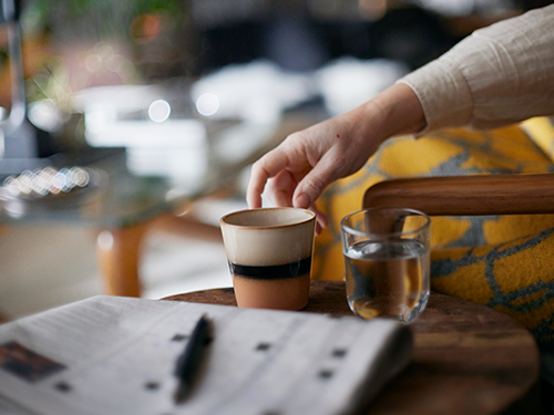 A close up image of a hand reaching for a coffee cup in London