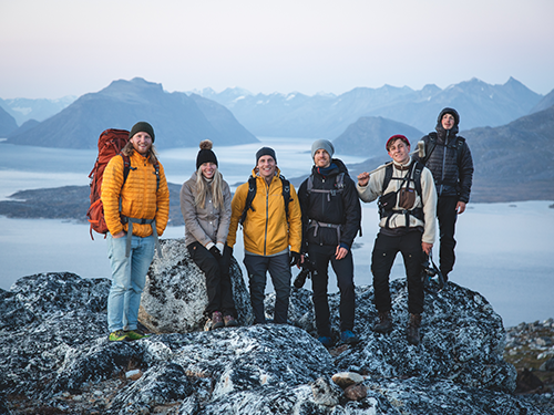 A group of friends smiles into the camera from a beautiful viewpoint in Southern Greenland 