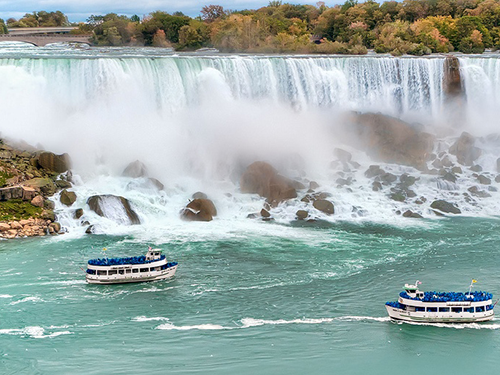 Niagara Falls pictured here with two blue boats in the water beneath 